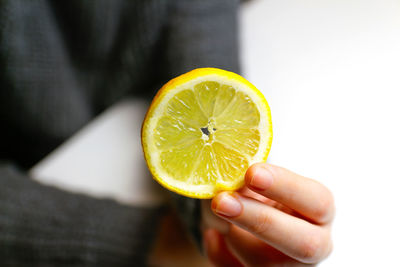 Female hand holding one yellow slice lemon fruit. hand holds lemon slice on white background.