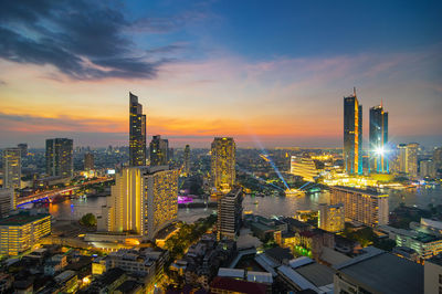 High angle view of illuminated city buildings against sky during sunset