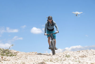 Low angle view of man riding bicycle against sky