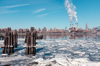 Panoramic view of river by buildings against blue sky