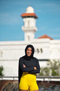 Portrait of woman standing against building