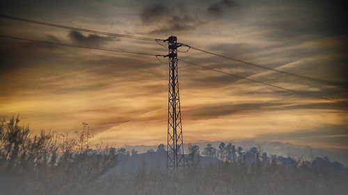 Low angle view of silhouette electricity pylon against sky during sunset