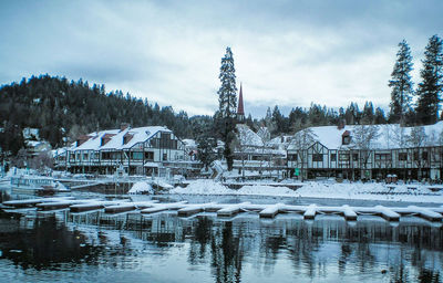 Frozen lake by buildings against sky during winter