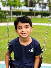 Portrait of boy on swing at playground