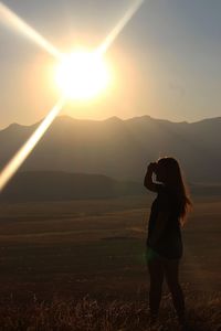 Full length of woman standing on field against sky during sunset