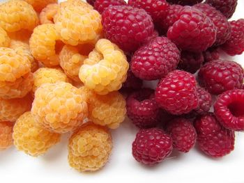 Close-up of red and yellow raspberries on white background