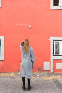 Rear view of woman standing against red wall