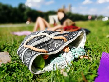 Close-up of hand bag on grass against cloudy sky