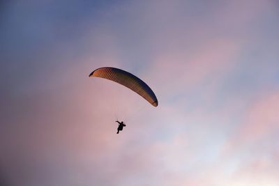 Low angle view of person paragliding against sky