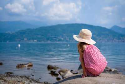 Rear view of little girl wearing hat standing at beach
