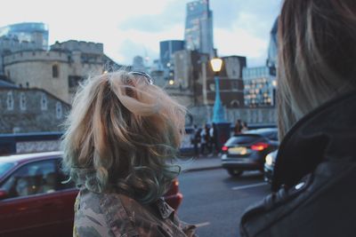 Rear view of woman in city against sky