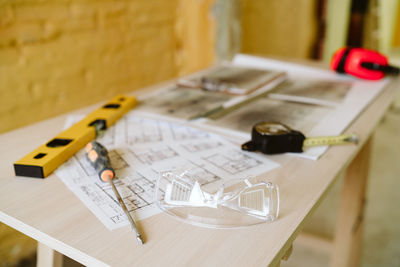 Blueprints, ear defenders, protection glasses and tools on architect workspace at construction site