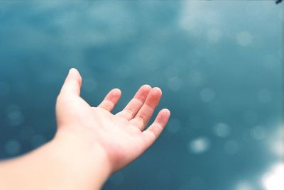 Close-up of cropped hand against sky