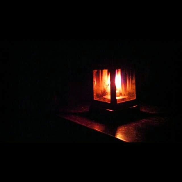VIEW OF LIT CANDLE IN DARK ROOM