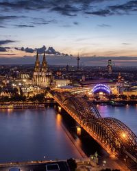 Illuminated bridge over river against sky in city at night