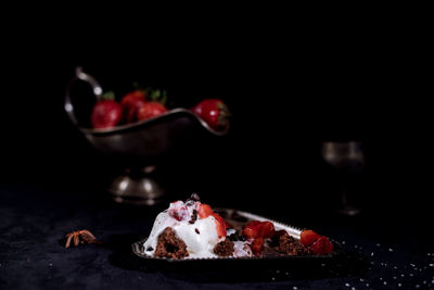 Close-up of strawberries with chocolate on table against black background