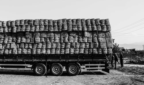 Stack of hay bales on truck against sky