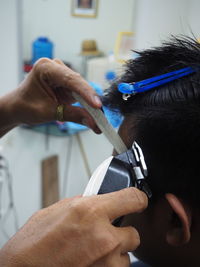 Cropped hands of barber cutting customer hair in salon