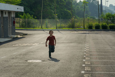 Full length of boy on road against trees