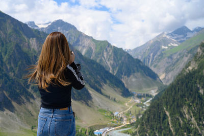 Rear view of woman in mountains against sky