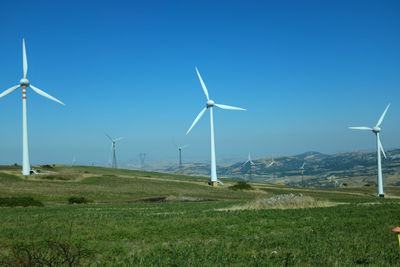 Windmill on field against blue sky