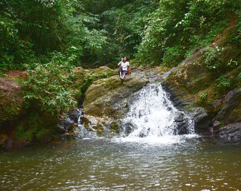 Rear view of man standing in waterfall