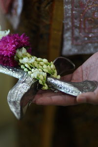 Close-up of hand holding metal and floral garland