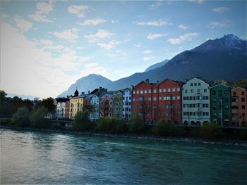 Buildings by lake against sky