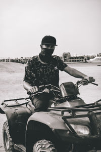 Man riding motorcycle sitting in sunglasses against clear sky