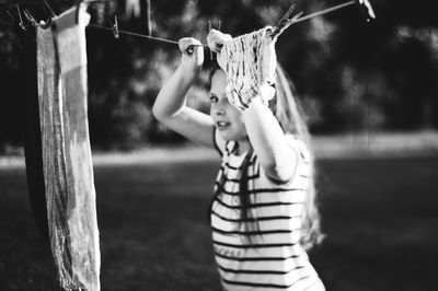 Girl holding clothesline while standing in yard