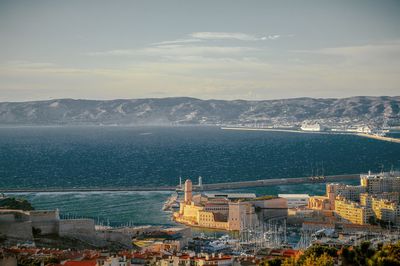 High angle view of cityscape by sea against sky