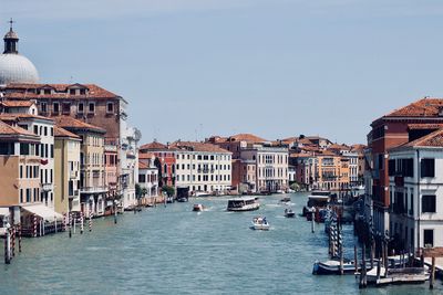 Boats in canal amidst buildings in city against clear sky