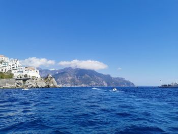 Scenic view of sea by buildings against clear blue sky