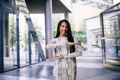 Portrait of smiling young woman standing against the wall