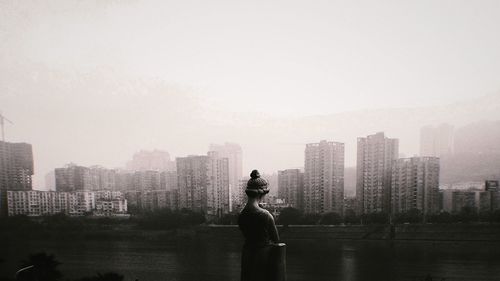 Man looking at city buildings against sky