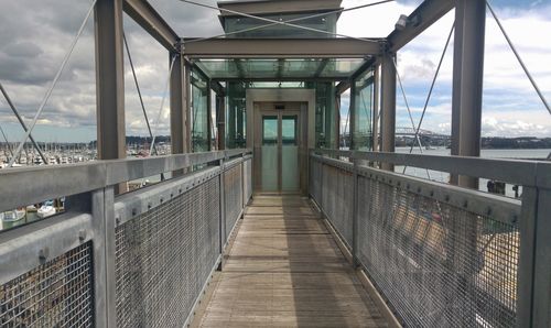 Footbridge in city against sky