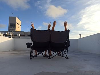 Man sitting on chair against sky