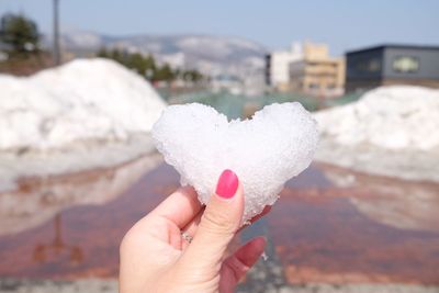 Close-up of cropped hand holding heart shaped ice during winter