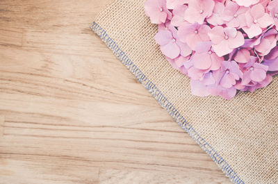 High angle view of pink hydrangeas on place mat over wooden table