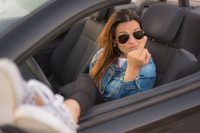 Portrait of smiling carefree woman sitting in convertible car