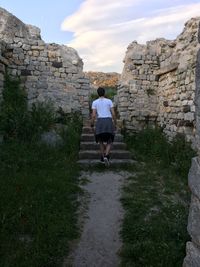 Rear view of man walking on stone wall