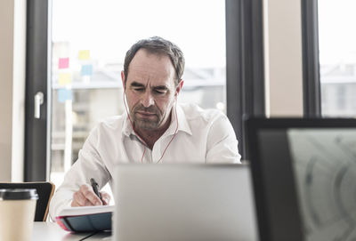 Businessman with earbuds working at desk in office