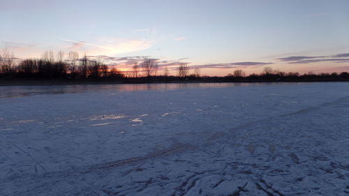 Scenic view of frozen lake against sky during sunset