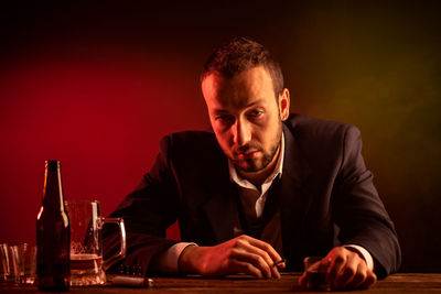 Young man sitting at table against gray background