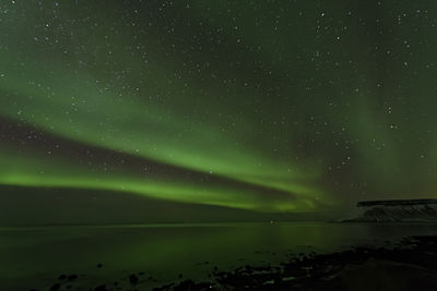 Scenic view of sea against aurora borealis at night