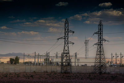 Low angle view of electricity pylon against sky during sunset