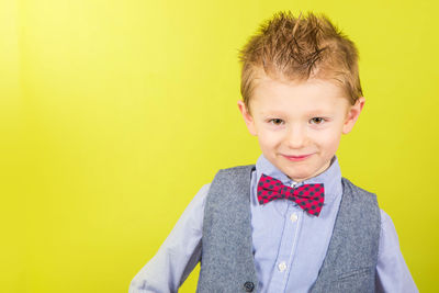 Portrait of boy standing against yellow background