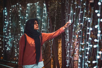 Full length of woman standing against fence in winter