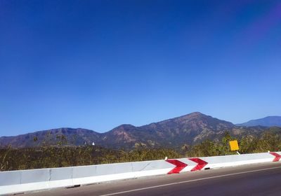 Road by mountains against clear blue sky