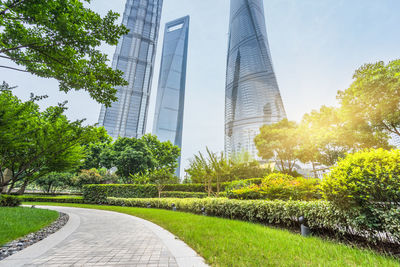 Footpath amidst trees and buildings against sky